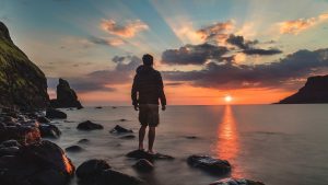 man looking across lake at sunset