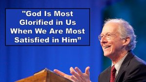 the man, John Piper, behind pulpit preaching vs blue background