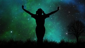 black silhouette of girl with outstretched arms looking at night sky